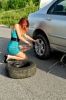 14201279-pretty-girl-is-trying-to-change-a-tire-on-a-road.jpg